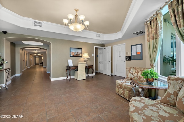 living room with a chandelier, a tray ceiling, and ornamental molding