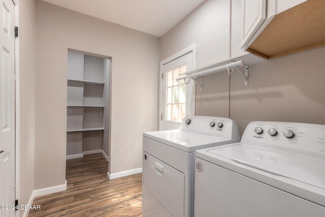 washroom featuring cabinets, washing machine and dryer, and dark hardwood / wood-style floors