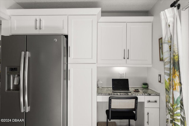 interior space featuring stainless steel refrigerator with ice dispenser, stone countertops, and white cabinets