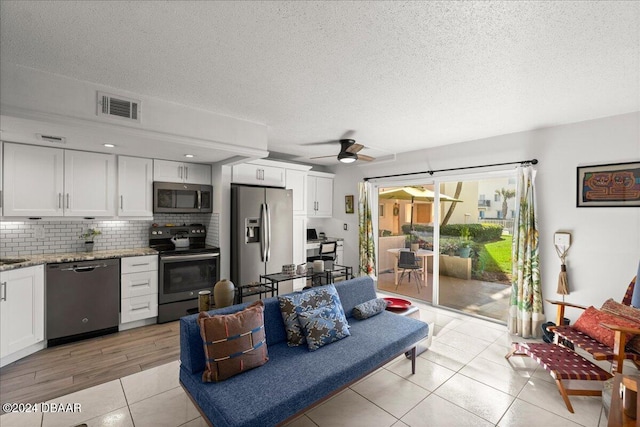 tiled living room with a textured ceiling and ceiling fan