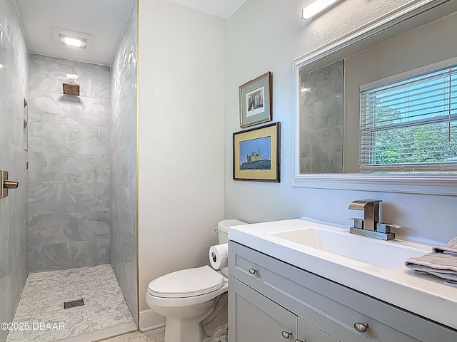 bathroom featuring a tile shower, toilet, and vanity