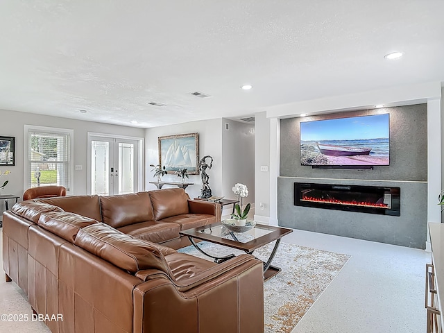 living area with a glass covered fireplace, recessed lighting, and dark speckled floor