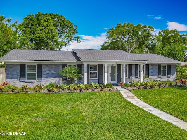 single story home featuring a front yard, a porch, a shingled roof, and brick siding