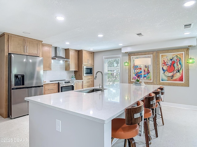 kitchen featuring stainless steel appliances, a sink, wall chimney exhaust hood, baseboards, and recessed lighting