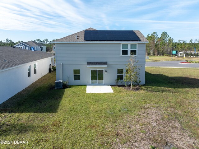 back of house featuring solar panels, a patio area, a yard, and central AC