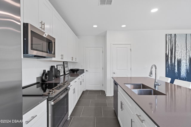 kitchen with white cabinets, sink, stainless steel appliances, and dark tile patterned flooring