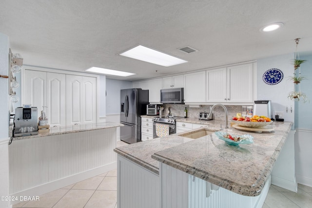 2937 S Atlantic Ave Unit 1504, Daytona Beach Shores, FL 32118 - kitchen with stainless steel appliances, a sink, a peninsula, light stone counters, and light tile patterned floors