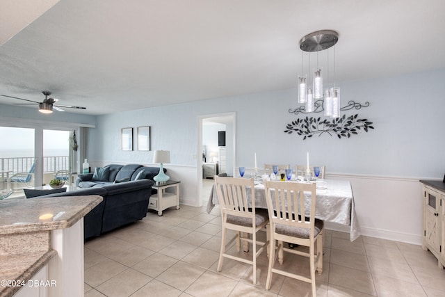 dining room featuring ceiling fan, light tile patterned floors, and a water view