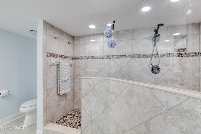 bathroom featuring toilet, tiled shower, and tile patterned floors