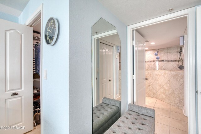2937 S Atlantic Ave Unit 1504, Daytona Beach Shores, FL 32118 - full bathroom featuring a tile shower, a spacious closet, and tile patterned floors
