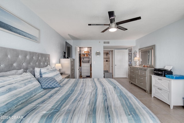 bedroom with a closet, a walk in closet, light tile patterned floors, and ceiling fan