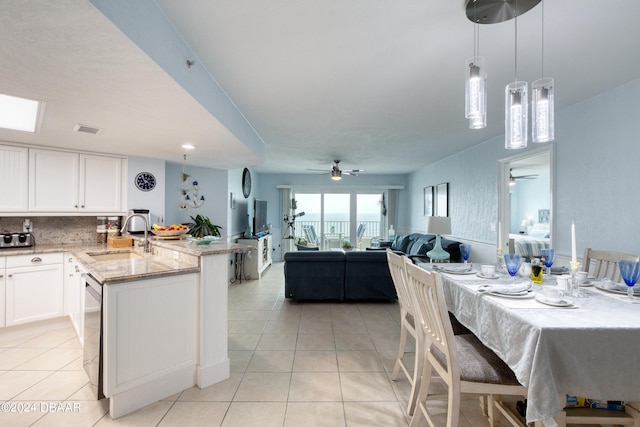 kitchen featuring white cabinetry, sink, light stone counters, ceiling fan, and pendant lighting