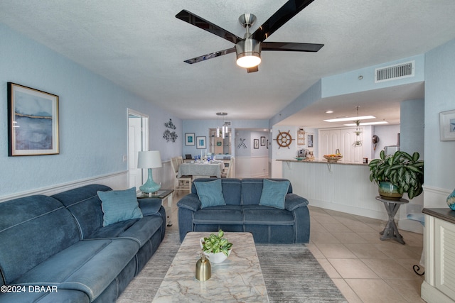 tiled living room with a textured ceiling and ceiling fan