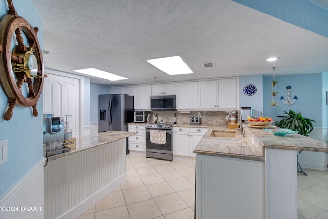 kitchen with tasteful backsplash, light tile patterned flooring, stainless steel appliances, white cabinetry, and sink