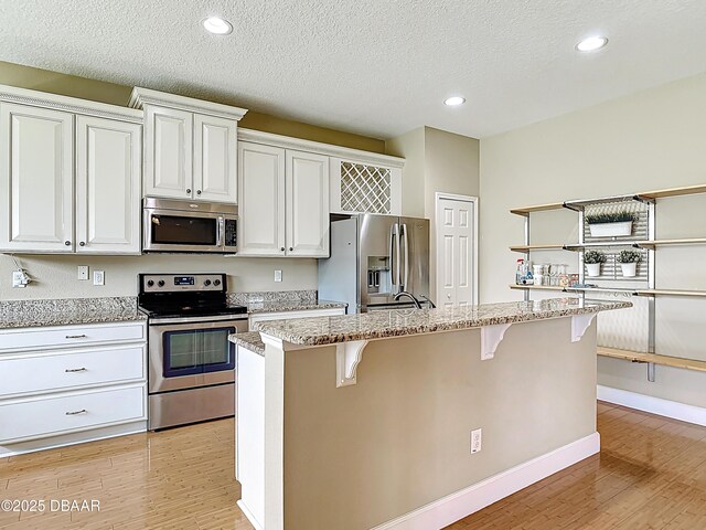 417 Grande Sunningdale Loop, Daytona Beach, FL 32124 - kitchen with stainless steel appliances, open shelves, light wood-style flooring, a breakfast bar, and recessed lighting