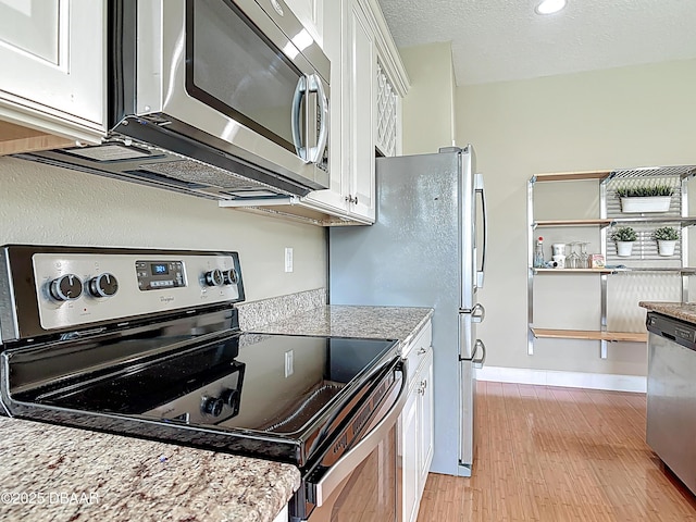 417 Grande Sunningdale Loop, Daytona Beach, FL 32124 - kitchen with stainless steel appliances, white cabinetry, light wood-style flooring, and baseboards