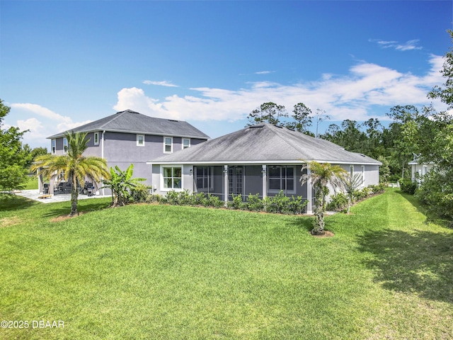 417 Grande Sunningdale Loop, Daytona Beach, FL 32124 - back of house featuring a lawn, a sunroom, and stucco siding