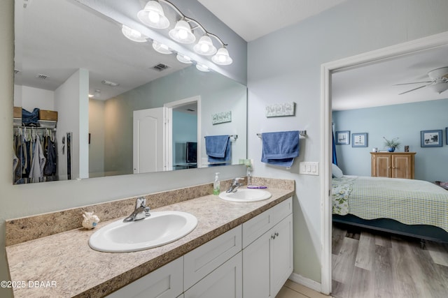 448 White Coral Ln, New Smyrna Beach, FL 32168 - bathroom featuring double vanity, ensuite bathroom, a spacious closet, a ceiling fan, and wood finished floors