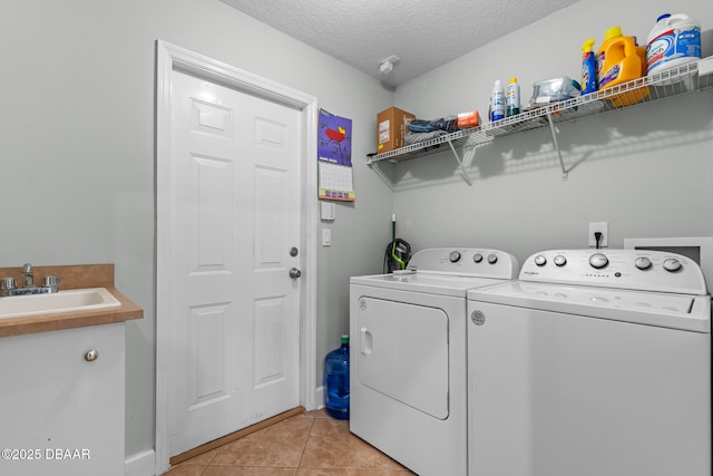 laundry room with laundry area, light tile patterned floors, washer and dryer, a textured ceiling, and a sink