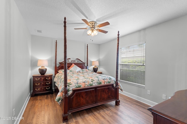 bedroom with baseboards, a textured ceiling, visible vents, and dark wood-type flooring