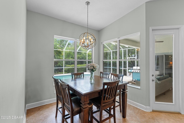 dining space with lofted ceiling, an inviting chandelier, baseboards, and a healthy amount of sunlight