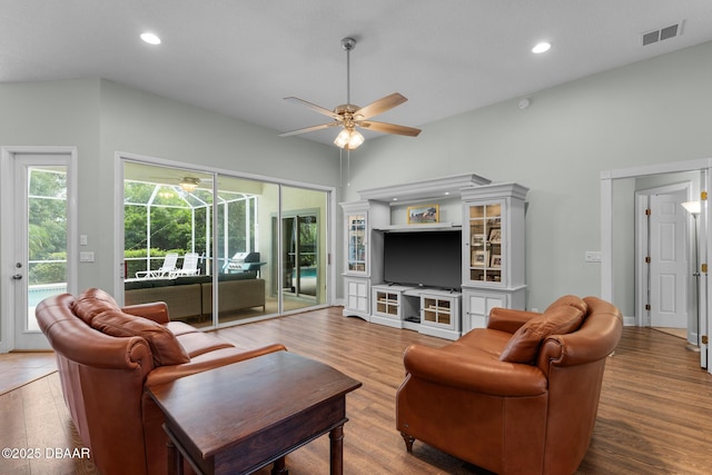 living area with a sunroom, visible vents, ceiling fan, and wood finished floors