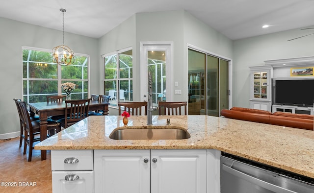 kitchen with hanging light fixtures, stainless steel dishwasher, white cabinetry, light stone countertops, and a chandelier