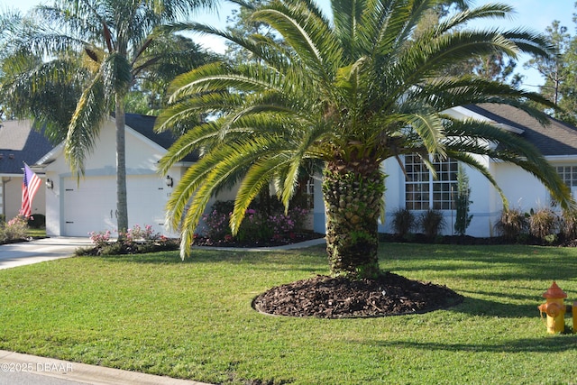 view of front of home with driveway, a front lawn, an attached garage, and stucco siding