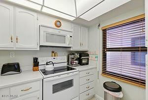4175 S Atlantic Ave Unit 405, New Smyrna Beach, FL 32169 - kitchen featuring white appliances, white cabinets, and light countertops