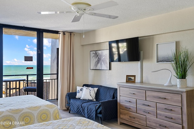 bedroom featuring multiple windows, expansive windows, a water view, and ceiling fan