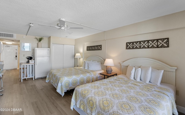 bedroom with ceiling fan, white refrigerator, a textured ceiling, and a closet