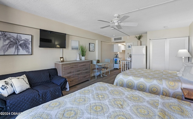 bedroom featuring ceiling fan, dark hardwood / wood-style floors, white refrigerator, a textured ceiling, and a closet