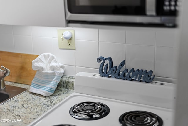 details featuring tasteful backsplash, white cabinetry, sink, and light stone countertops