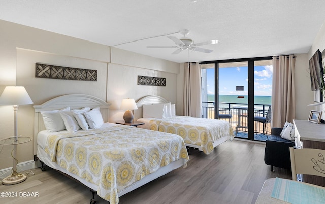 bedroom with hardwood / wood-style floors, expansive windows, ceiling fan, access to exterior, and a textured ceiling