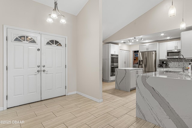 entryway with baseboards, high vaulted ceiling, an inviting chandelier, and wood tiled floor