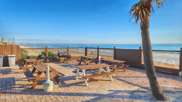 view of patio with a beach view, area for grilling, and a water view