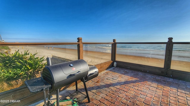 view of patio / terrace with grilling area, a water view, and a view of the beach