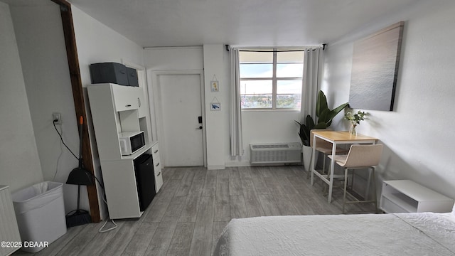 bedroom with light hardwood / wood-style flooring and a wall mounted air conditioner