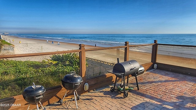 view of patio / terrace featuring a view of the beach, area for grilling, and a water view