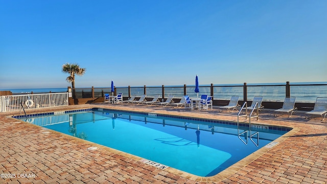 view of pool with a water view and a patio