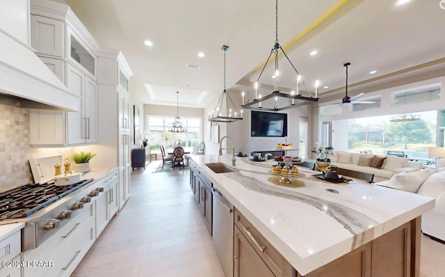 kitchen with sink, tasteful backsplash, a spacious island, decorative light fixtures, and white cabinets