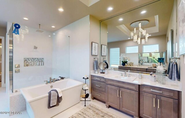 bathroom with a raised ceiling, a bath, a notable chandelier, tile patterned floors, and vanity