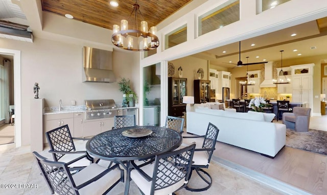 dining room with ceiling fan with notable chandelier, a towering ceiling, sink, and wood ceiling