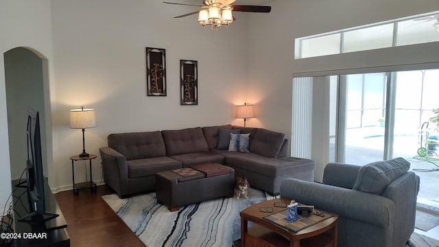 living room featuring dark wood-type flooring, a high ceiling, and ceiling fan