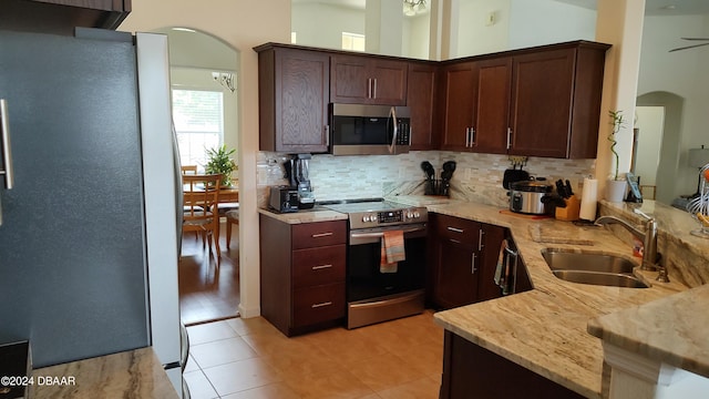 kitchen with stainless steel appliances, backsplash, dark brown cabinetry, sink, and light hardwood / wood-style floors