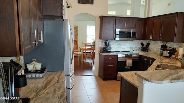 kitchen featuring decorative backsplash, sink, high vaulted ceiling, dark brown cabinets, and appliances with stainless steel finishes