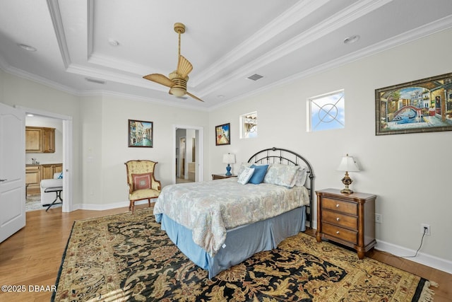 bedroom featuring crown molding, ensuite bath, ceiling fan, a tray ceiling, and light hardwood / wood-style floors