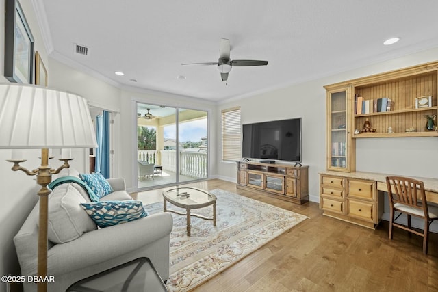 living room featuring ceiling fan, wood-type flooring, built in desk, and ornamental molding