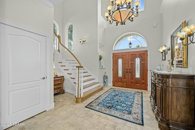 foyer entrance featuring a wealth of natural light, a chandelier, and a high ceiling