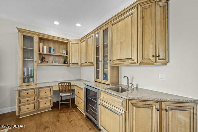 kitchen with dark hardwood / wood-style floors, built in desk, sink, wine cooler, and light stone counters